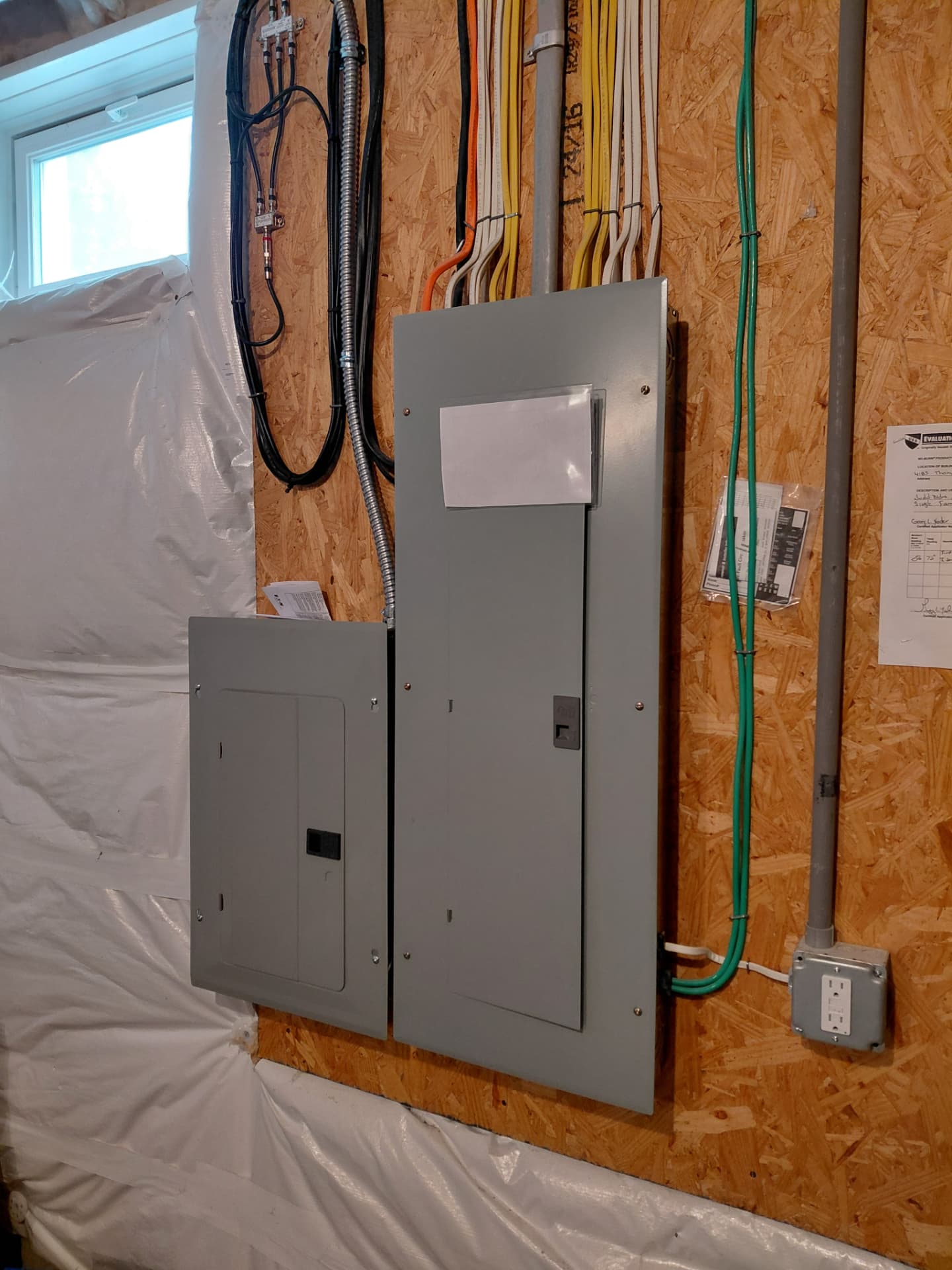 Main panel and subpanel with labeled circuits and neatly bundled cables in a basement