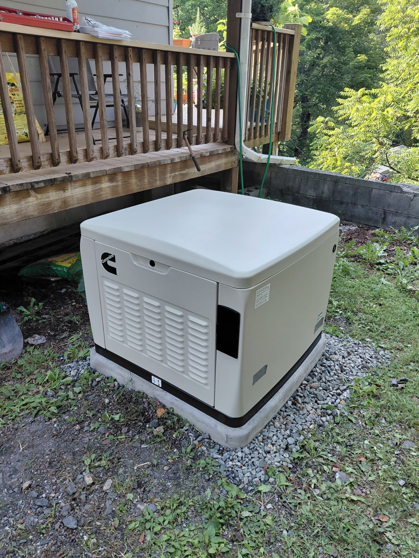 Home standby generator installed on a poured pad next to a rear deck