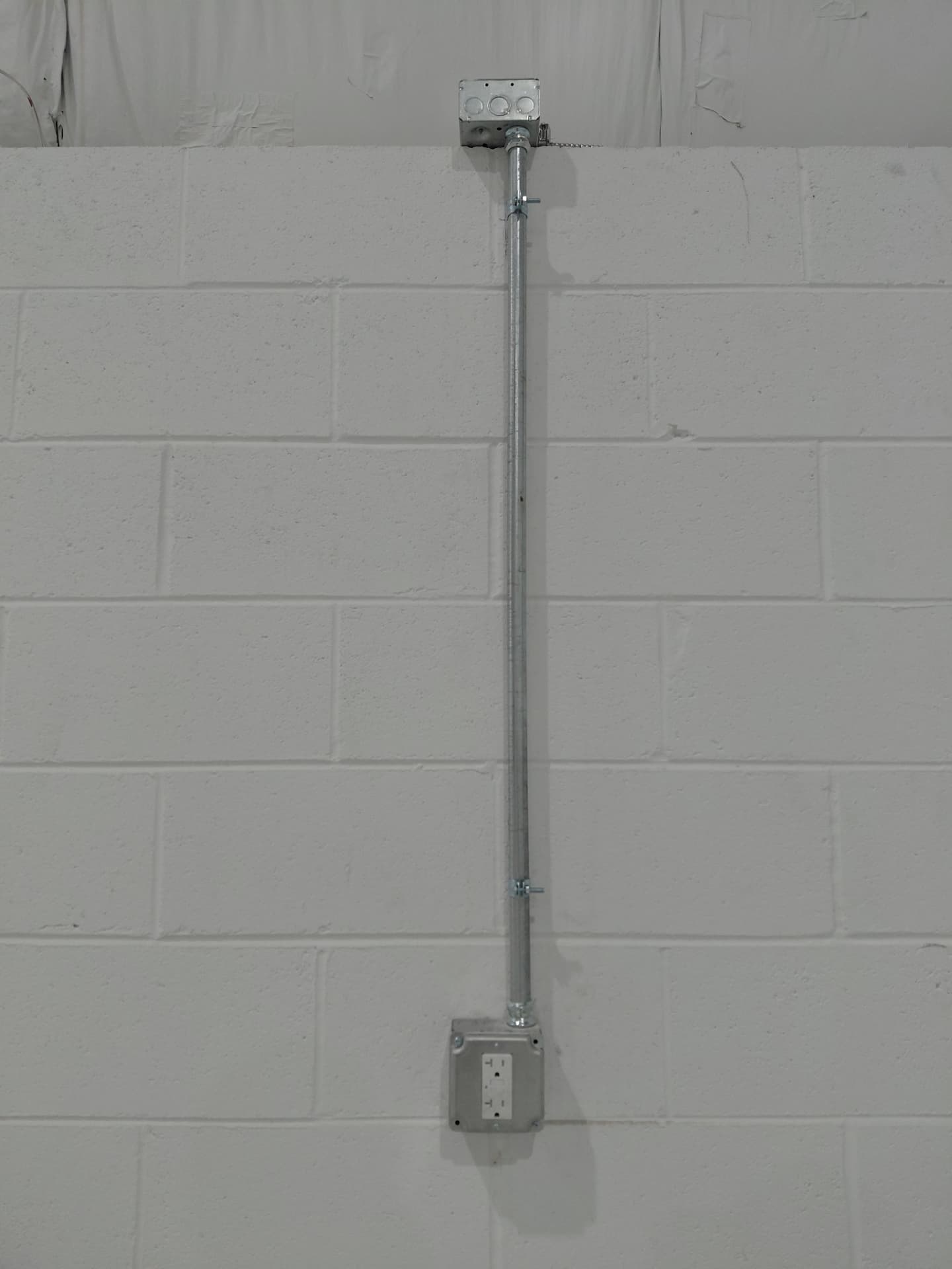Surface-mounted conduit run feeding a new GFCI receptacle on a block wall